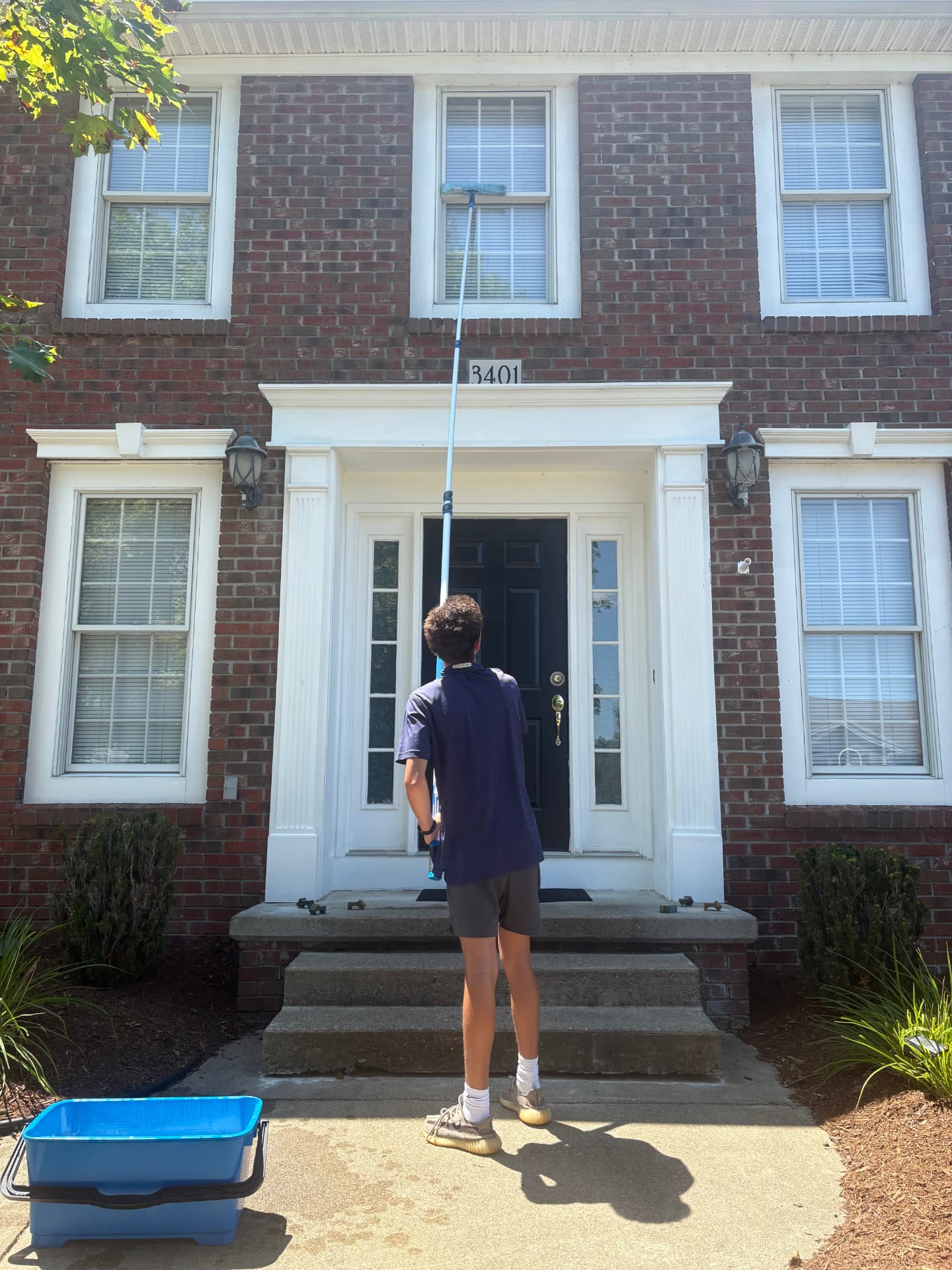 M&C Pane Patrol technician cleaning windows on a brick home with a water-fed pole